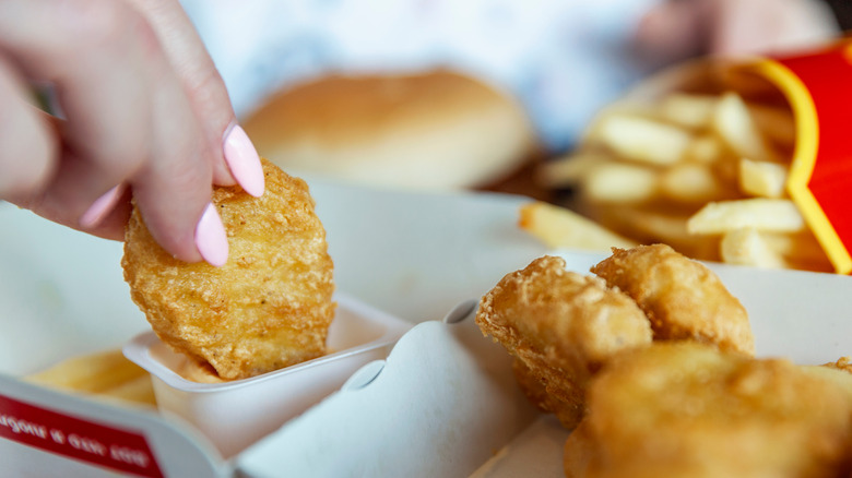 Someone dips McDonald's chicken nuggets in a sauce