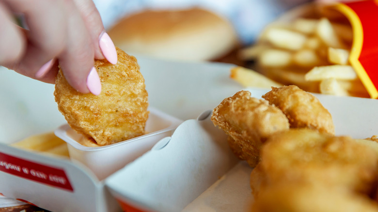 Someone dips McDonald's chicken nuggets in a sauce
