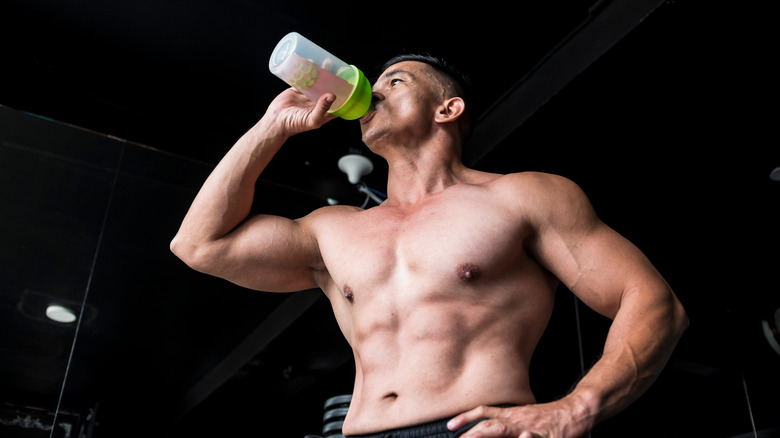 A man drinks a pre-workout supplement at the gym