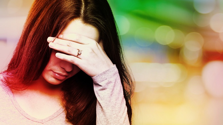 Woman with migraine with hand to head