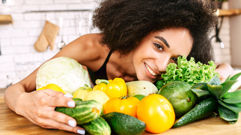 Smiling dark-haired woman cradling vegetables 