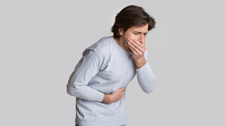 man clutching stomach and mouth