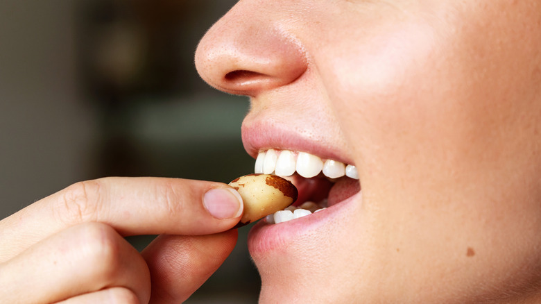A woman eating a Brazil nut