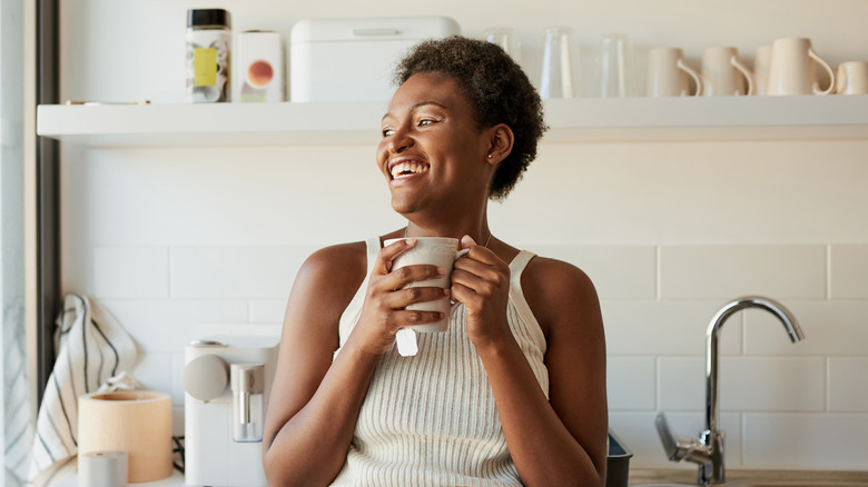 smiling woman drinking out of a mug