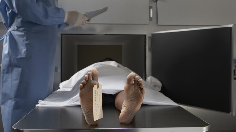 man with toe tag lying on table in morgue