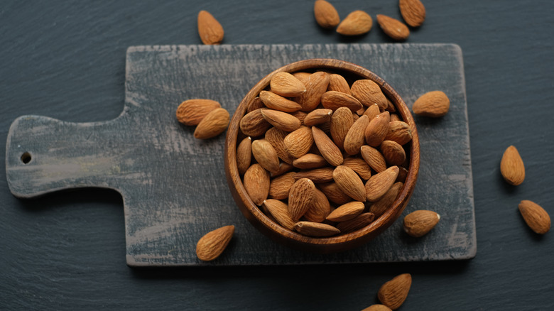A bowl of almonds on a cutting board