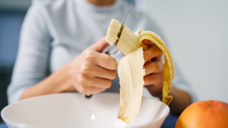 A woman slices a banana