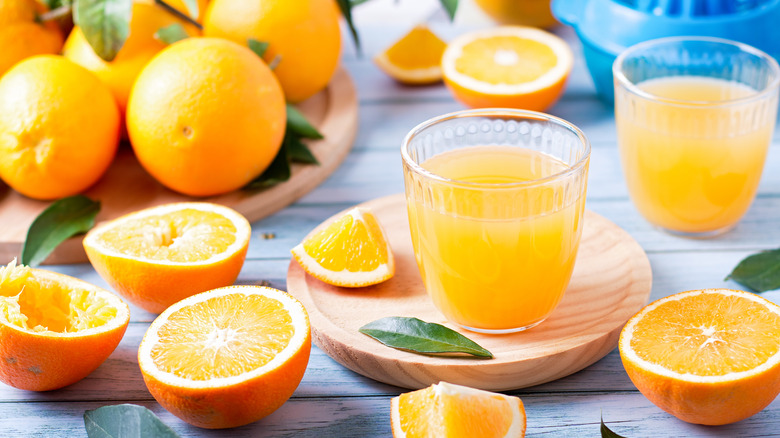 A glass of orange juice surrounded by oranges