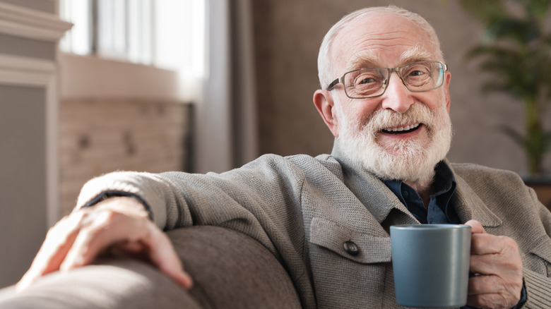 smiling elderly man holding mug