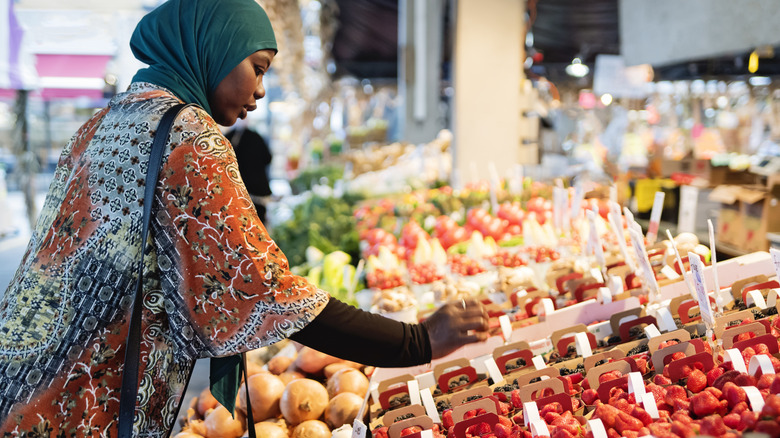 woman looking at fruit at outdoor market stand