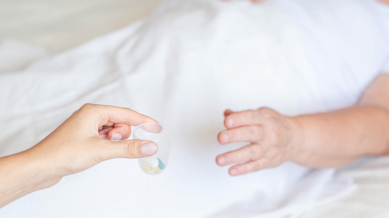 Bedridden patient being handed medication