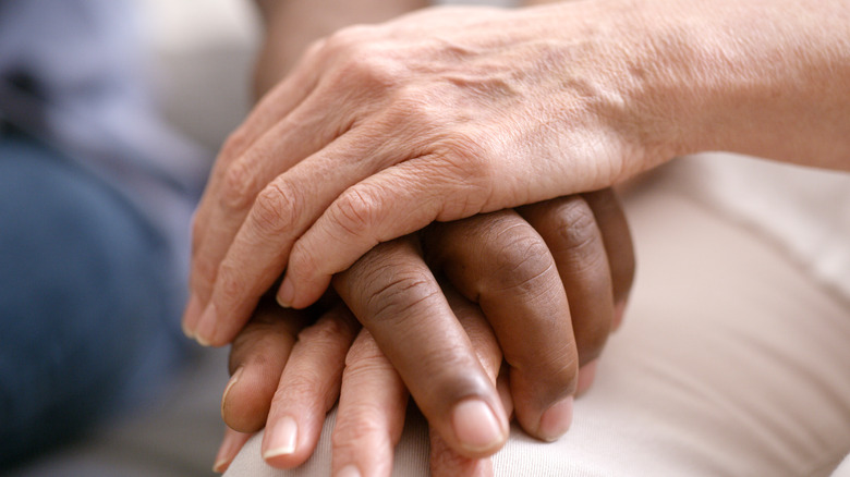 person's hand on ill patient's hand