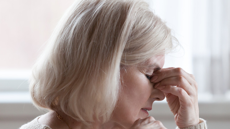 Anxious woman sits with her eyes closed and fingers at the bridge of her nose