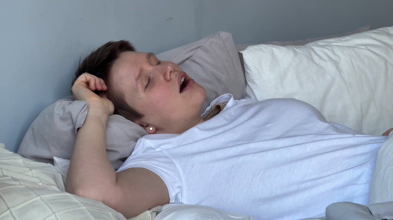 A young woman sleeping on her back with her mouth open