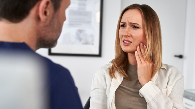 A woman talking to her dentist about her sore jaw
