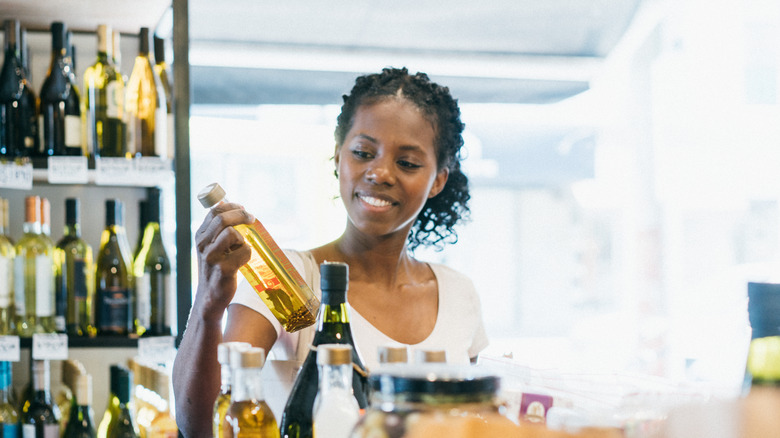 young woman examining a bottle of oil