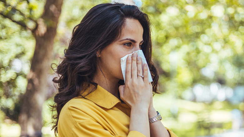 A woman walking outdoors covering her nose