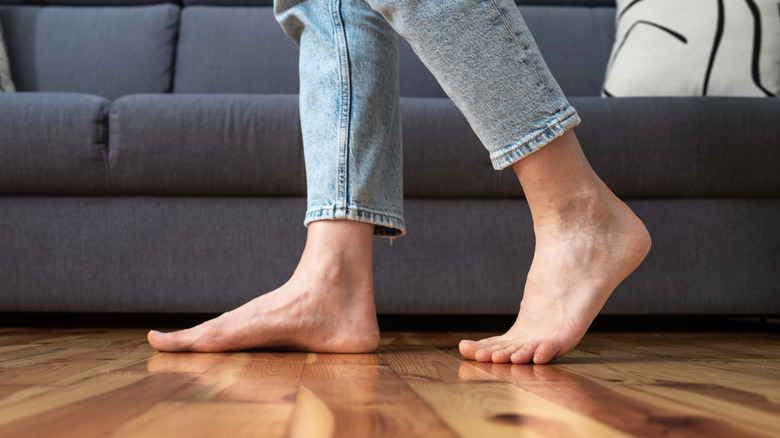 person in cropped jeans walking on wooden floor
