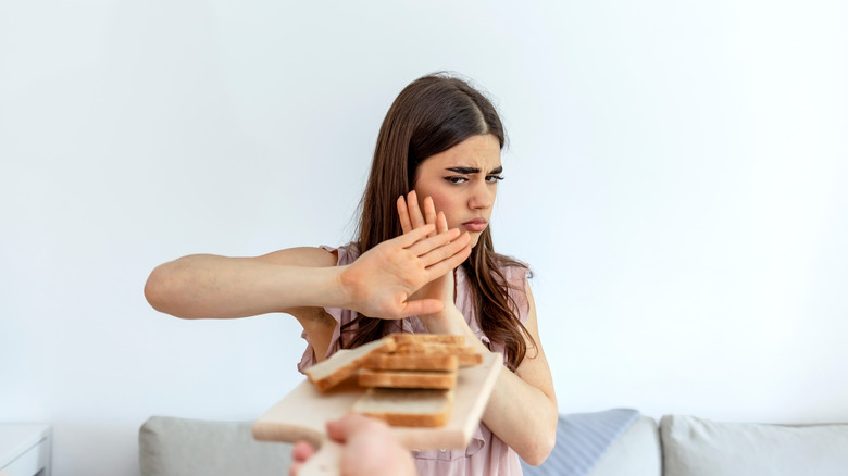 woman pushes away plate of bread 
