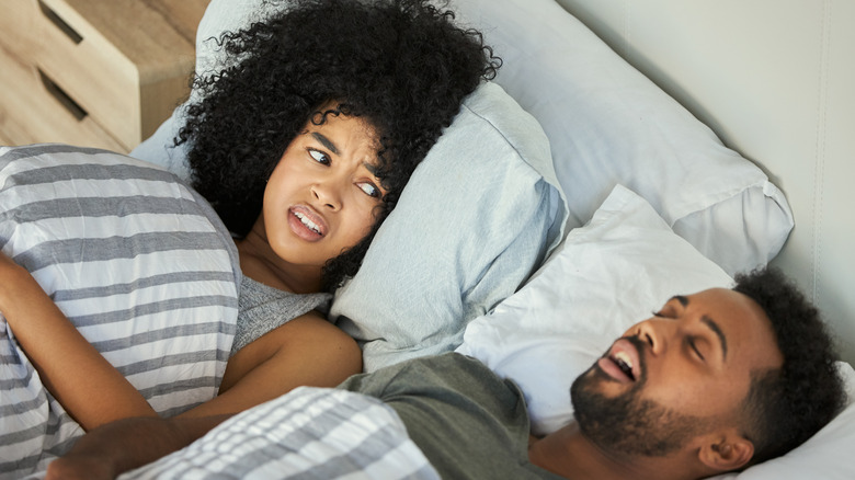 man sleeping with unhappy woman beside him