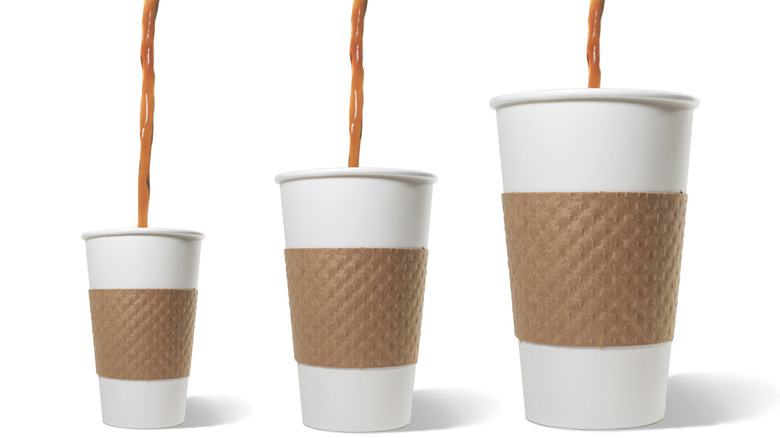 3 different size disposable coffee cups with coffee getting poured in each