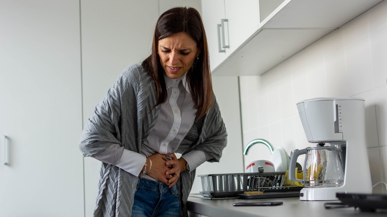 A woman is holding her stomach in pain