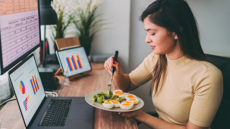 woman eating hard-boiled eggs at work 