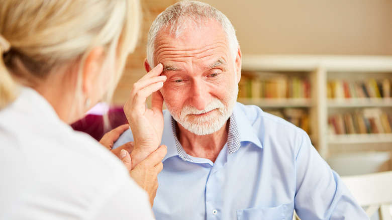 Older man holding head