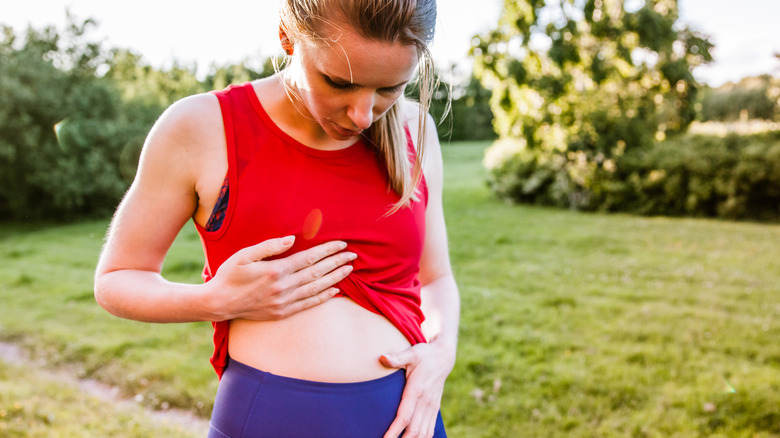 woman outdoors holding her stomach