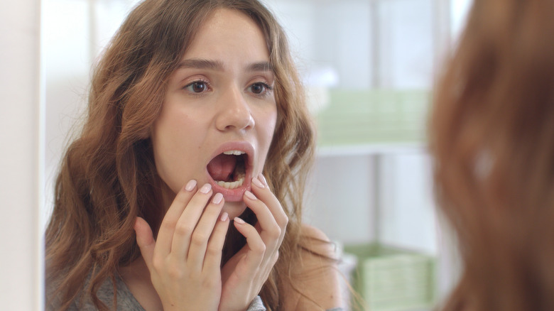 woman looking at her teeth in the mirror