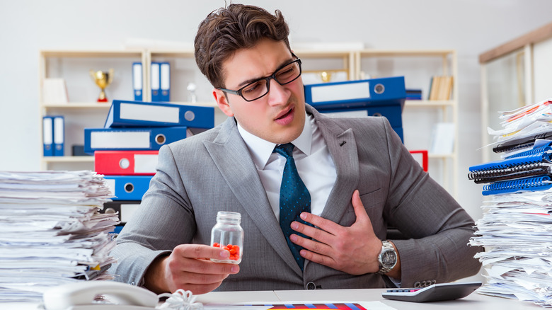 business man in suit stressed out taking heartburn pill