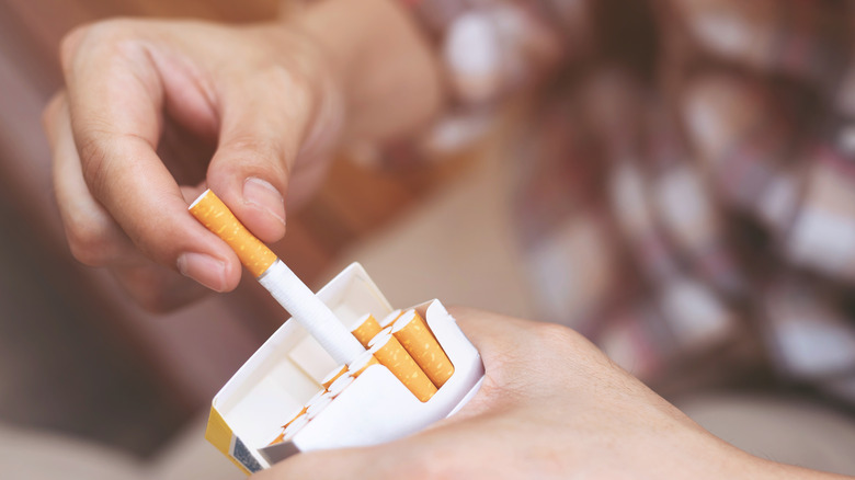Hand pulling cigarette out of carton