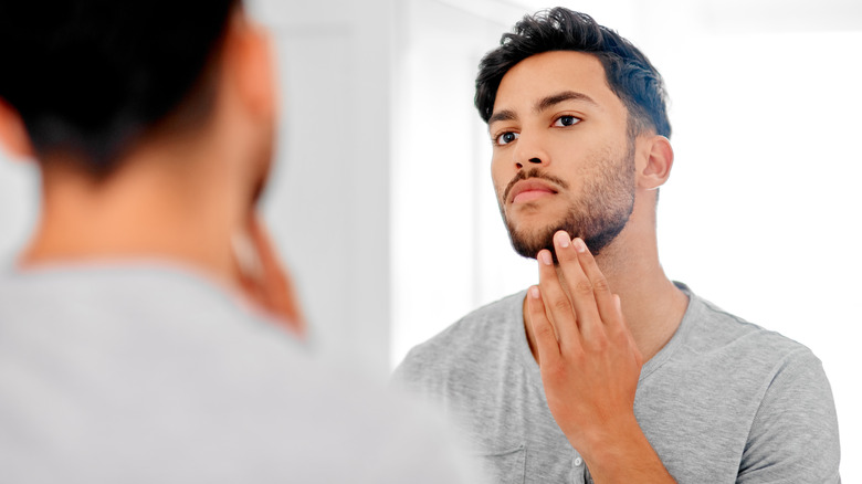 Man examining face in mirror