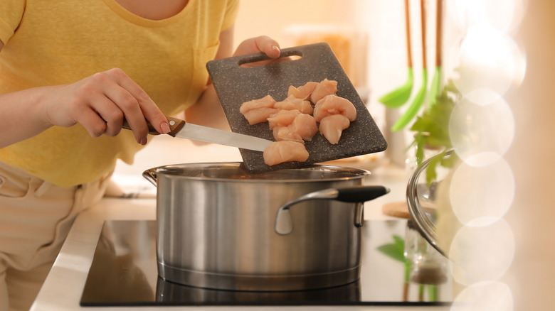 woman putting chicken into pot
