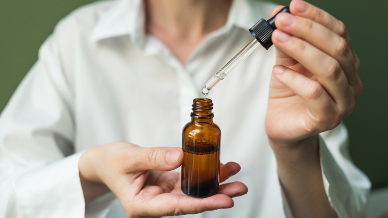 Hands holding essential oils dropper