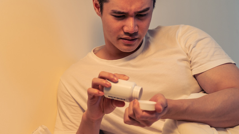 young man taking supplements at night
