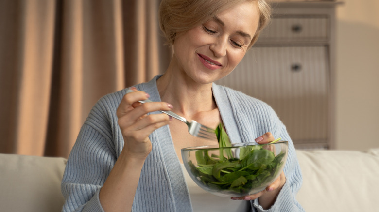 woman eating a bowl of spinach salad