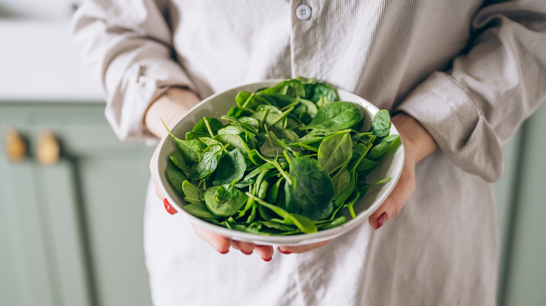 A woman's hands holding a bowl of spinach