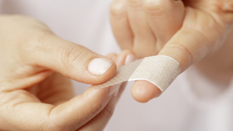 person putting bandaid on finger