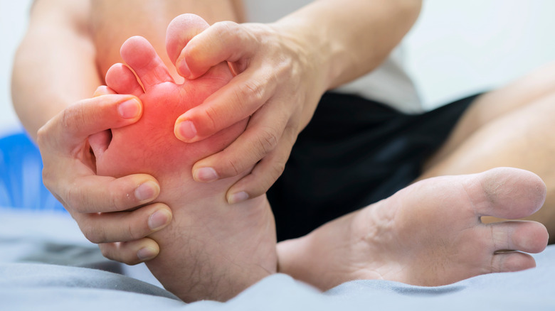 man holding toe that hurts because of gout