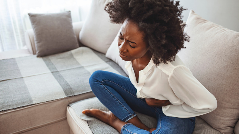 Woman on couch grimacing with cramps