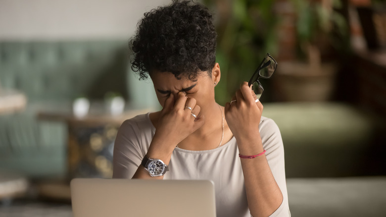 woman rubbing her eyes at computer