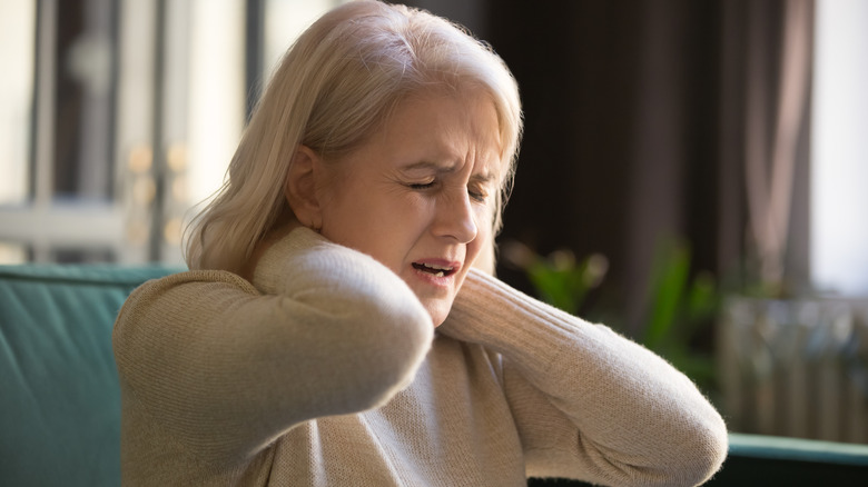 Woman with eyes closed rubbing neck