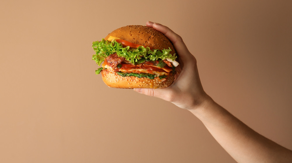 Hand holding large cheeseburger