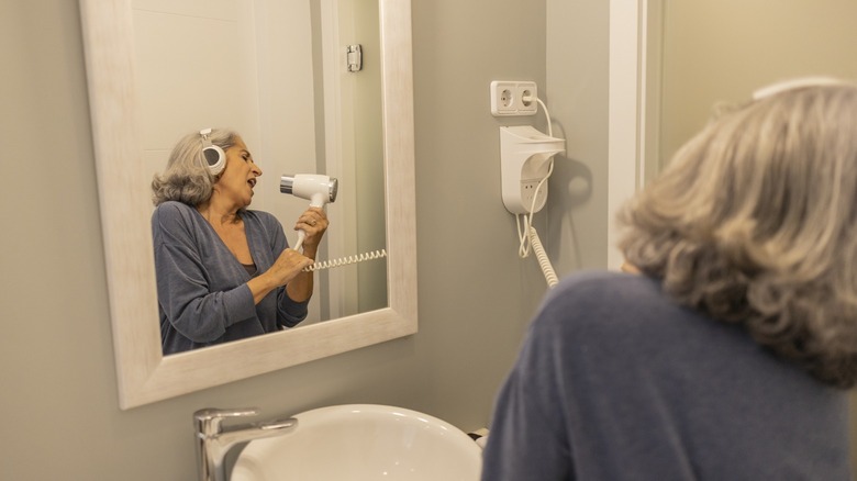 Lady singing in the toilet while using blower as mic