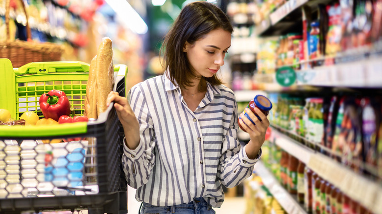 woman looking at the nutrition label of food while grocery shopping
