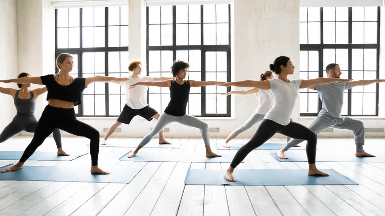 Group of people doing warrior two pose in yoga class﻿