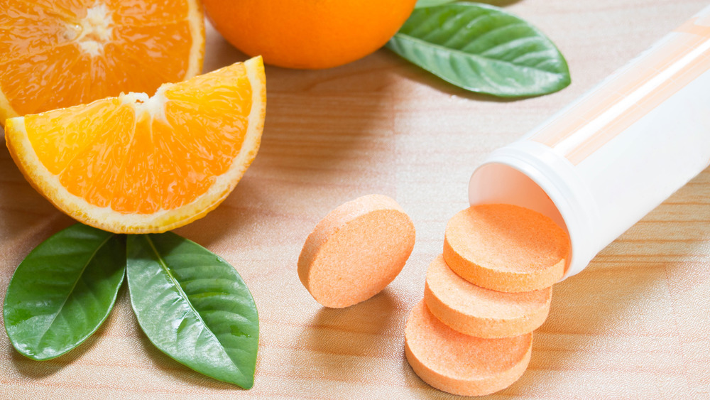 Vitamin C tablets and oranges