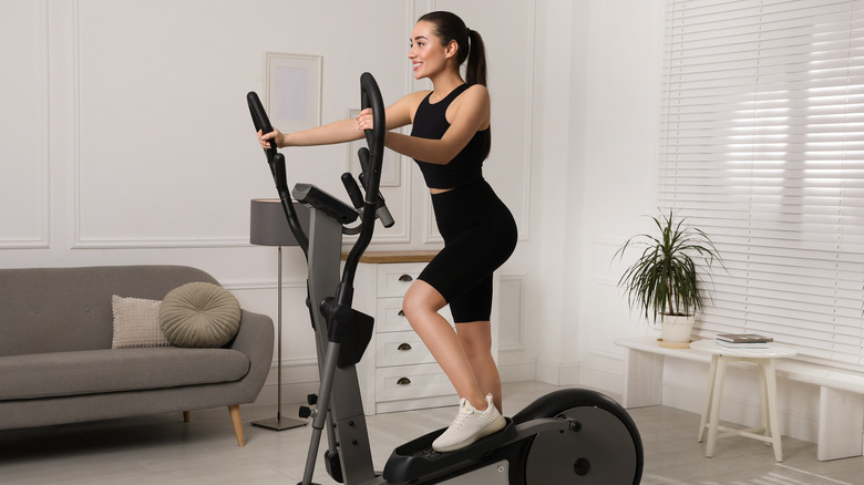 Happy young woman on elliptical machine