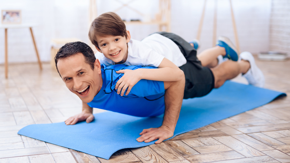 man doing pushups with son on back